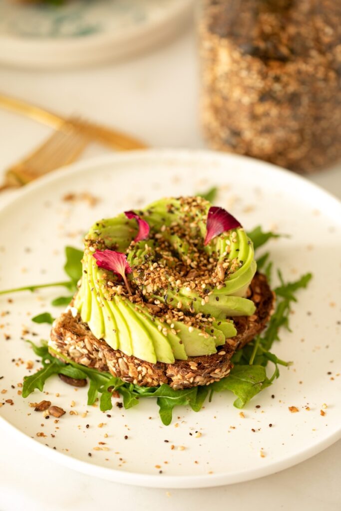 a white plate topped with a sandwich covered in avocado