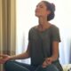 Woman Meditating In Bedroom